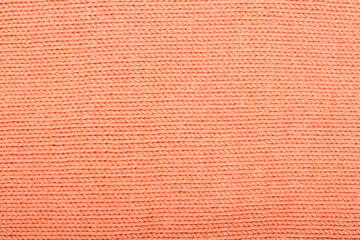 Sweater or scarf fabric texture large knitting. Knitted jersey background with a relief pattern. Wool hand- machine, handmade, orange.