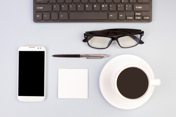 Tablet, calculator, phone, pen and a cup of coffee, lot of things on a light background. Top view with copy space.