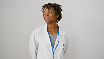 A contemplative young black woman with dreadlocks wearing a lab coat and lanyard isolated against a white background.
