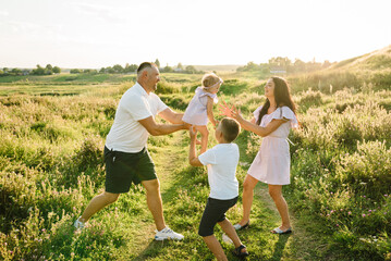 Family spending time together outdoors. A happy family, mother, father, and son throw up their baby...