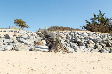 Accès à une plage par un escalier fait de gros blocs de granit aidé par une rampe en cordage....