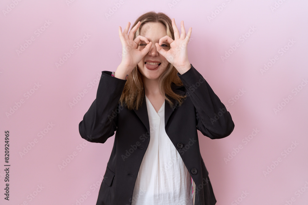 Wall mural young caucasian business woman wearing black jacket doing ok gesture like binoculars sticking tongue