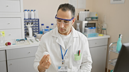 Hispanic scientist analyzes petri dish in a laboratory setting, wearing lab coat and protective...