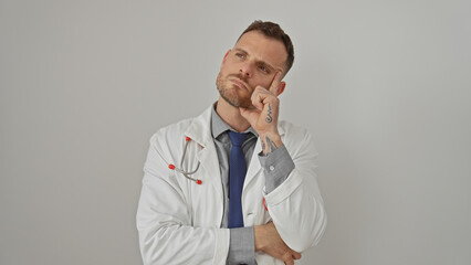 Pensive man in lab coat with tie and stethoscope over isolated white background looks contemplative.