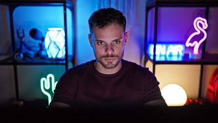 Portrait of a confident man with a beard in a dark gaming room with neon lights and modern decor