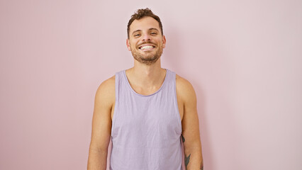 Smiling young hispanic man with beard in casual sleeveless shirt against a plain pink background