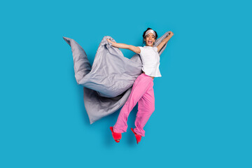 Full body portrait of pretty young woman hold blanket jump wear pajama isolated on blue color...