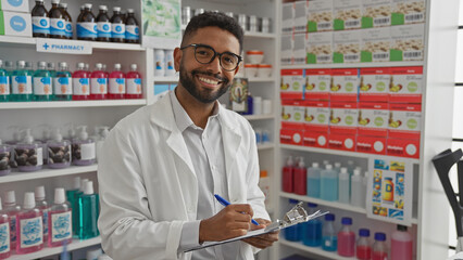 African american pharmacist smiling while taking notes in a well-stocked, modern pharmacy