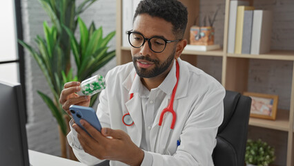 A professional african american male doctor examines medication while using a smartphone in a...