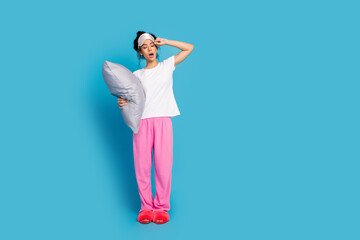 Portrait of pretty young woman hold pillow yawn wear pajama isolated on blue color background
