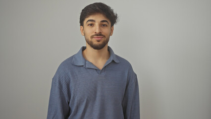 A young, handsome arab man with a beard posing in a blue shirt against an isolated white background.