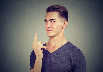 Portrait of a sly young man showing his index finger, making a promise for a best choice 
