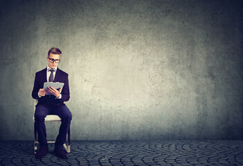 A job applicant sitting on a chair reading a contract  