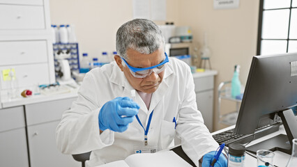 A mature man in a lab coat conducts research in a medical laboratory, meticulously analyzing...