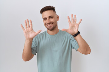 Hispanic man with beard standing over white background showing and pointing up with fingers number ten while smiling confident and happy.