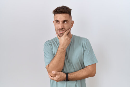 Hispanic man with beard standing over white background thinking worried about a question, concerned and nervous with hand on chin