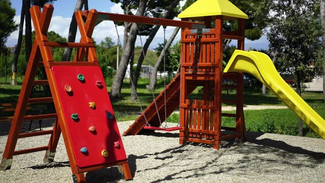 empty children playground in park with swing swinging on wind