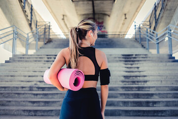 Shot of an attractive young woman standing alone and holding a yoga mat during her outdoor workout.