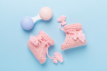 Pink baby booties and rattles on color background, top view