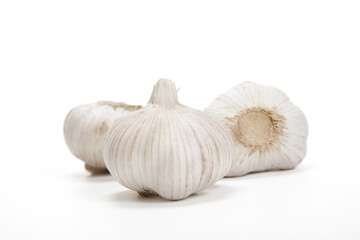 Three Whole Garlic Bulbs With Cloves on a White Background in Bright Daylight