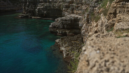 Scenic coastal cliffside in gallipoli, puglia, italy, showcasing rugged rocks and turquoise sea water in the vibrant european outdoor setting.