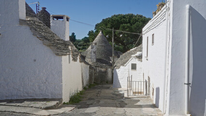 Traditional stone houses line a narrow street in alberobello, puglia, italy, highlighting the...