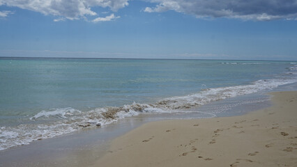 A serene, empty beach with soft sand and gentle waves under a clear, blue sky in pescoluse, salento, puglia, italy, capturing the essence of tranquility and natural beauty.