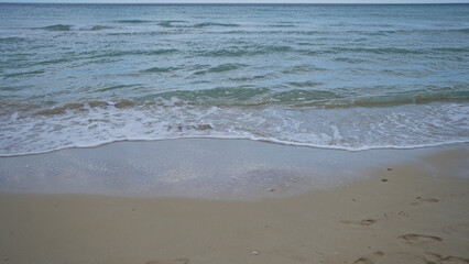 Serene sandy beach in pescoluse, salento, puglia, italy with gentle waves meeting the shore on a tranquil day.