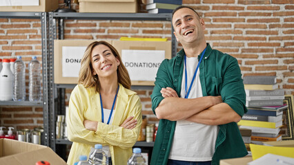 Man and woman volunteers standing together with arms crossed gesture smiling at charity center