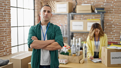 Man and woman volunteers standing with arms crossed gesture working at charity center