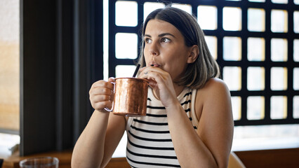 Young beautiful hispanic woman drinking a tropical cocktail drink at the restaurant