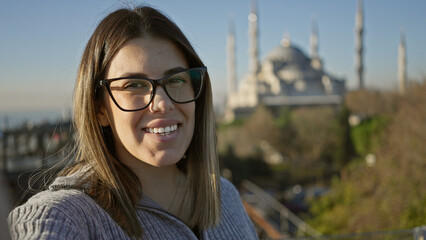 Smiling young woman wearing glasses with the blue mosque in istanbul, turkey in the background