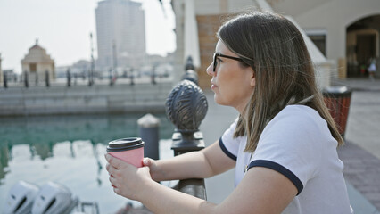 Serene young woman enjoying a coffee by the modern doha skyline in qatar.