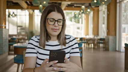 A young woman using a smartphone in a modern cafe, embodying a casual, connected lifestyle.