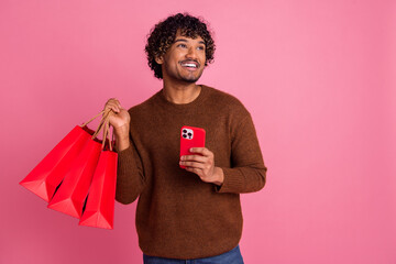 Photo of cheerful positive man wear trendy brown clothes hold purchase empty space isolated on pink...