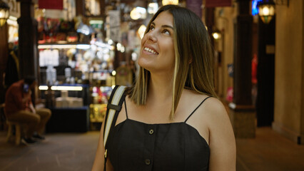 Smiling young adult hispanic woman enjoying her visit at dubai's traditional souk madinat jumeirah.