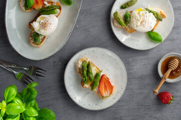 Toast bruschetta with grilled asparagus, poached egg, strawberry and fresh cream cheese. Sourdough bread with vegetables and egg. Food photography. Healthy breakfast, brunch. Summer food