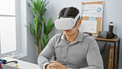 A young asian man wearing virtual reality glasses in a modern office setting.