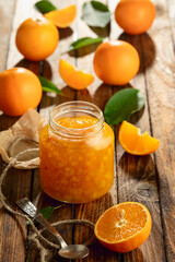 Orange jam and fresh fruits on an old wooden table.