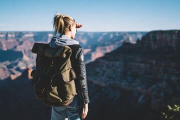 Back view of female traveler observing beautiful nature landscape on Grand Canyon, hipster woman...