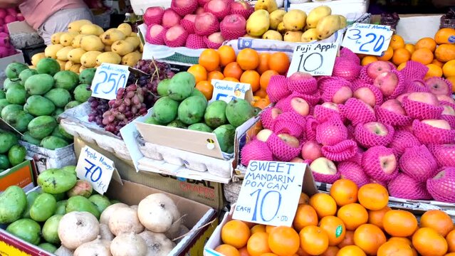 Varieties of fruits such as apples, oranges, unripe green mangoes, grapes, and many more are on display.