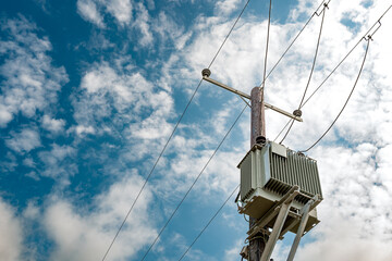 Newly installed, next generation electrical transformer mounted on a wooden pole. The power lines...