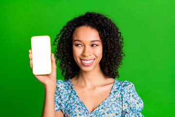 Photo of nice young woman demonstrate empty space phone screen wear top isolated on green color...