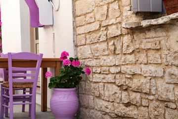 view of greek or mediterranean street cafe with lilac color decoration and natural stone brick wall