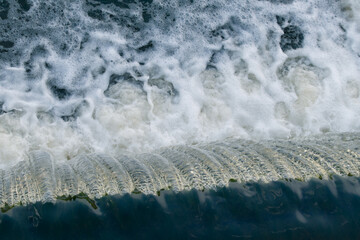 Streams of water fall from a water dam. Water foam.
