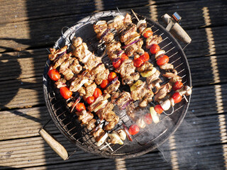 Smoky garden grill on the terrace. Skewers of poultry meat and spring vegetables. 