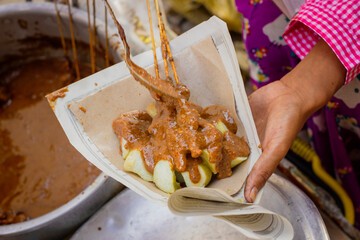 Close up of chicken satay with rice cake or called lontong is preparing by the seller 