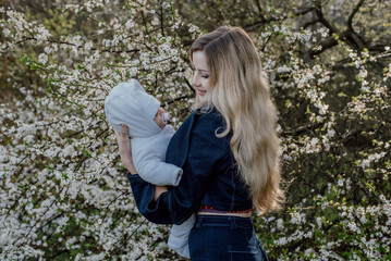 young beautiful mother with her newborn baby outdoors enjoying the spring 