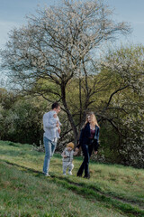 Fototapeta premium happy and cheerful young family with two kids enjoying spring sun outdoors. Young parents with kids playing outdoors