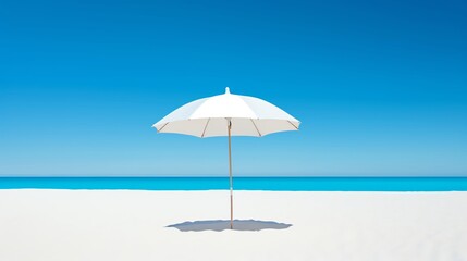 White beach umbrella on the sandy beach with blue ocean and clear blue sky in the background.